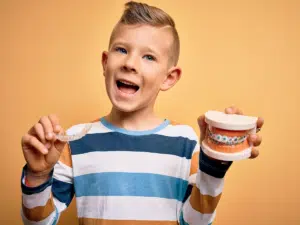 Child holding orthodontic models that demonstrate early bite correction options