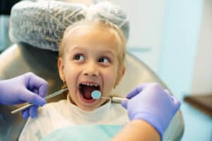 Child receiving a dental exam that highlights early orthodontic treatment benefits during growth