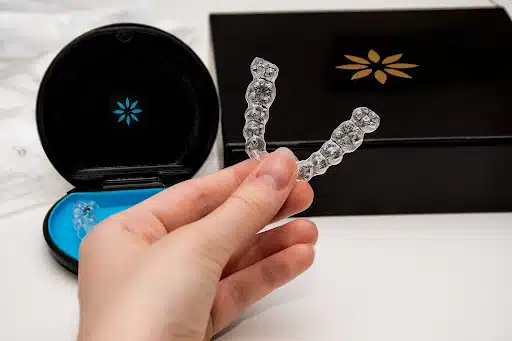 Hand holding clear aligner trays with case during Invisalign vs Spark aligners clear aligner comparison